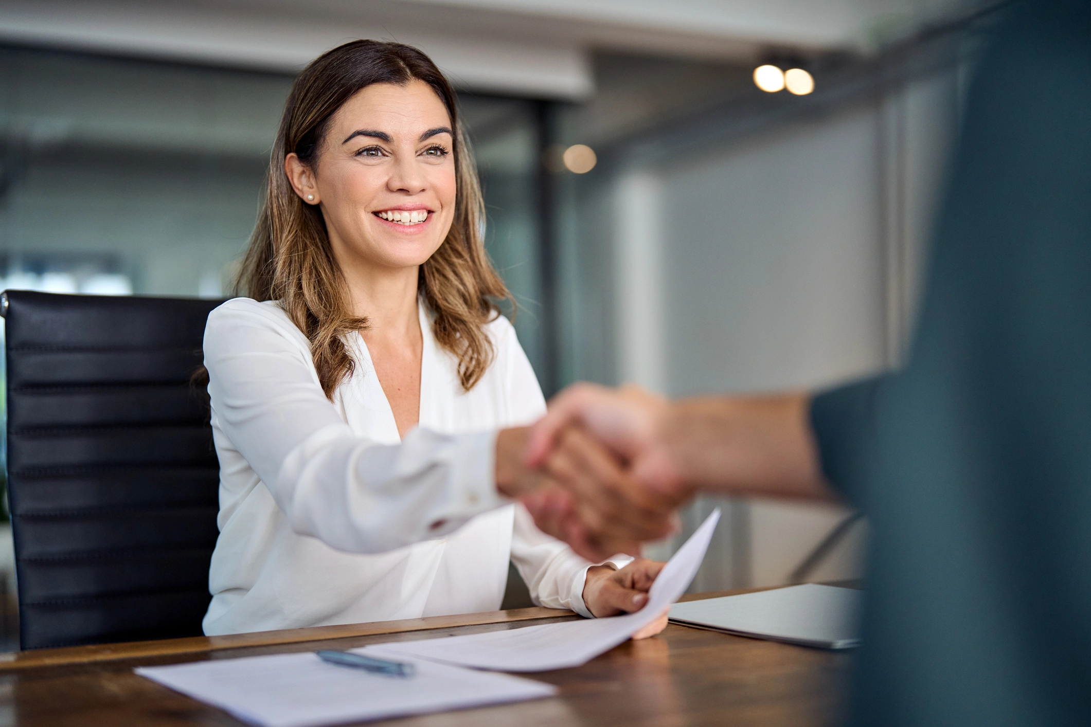 Young Female Banker Shaking Hands At Desk