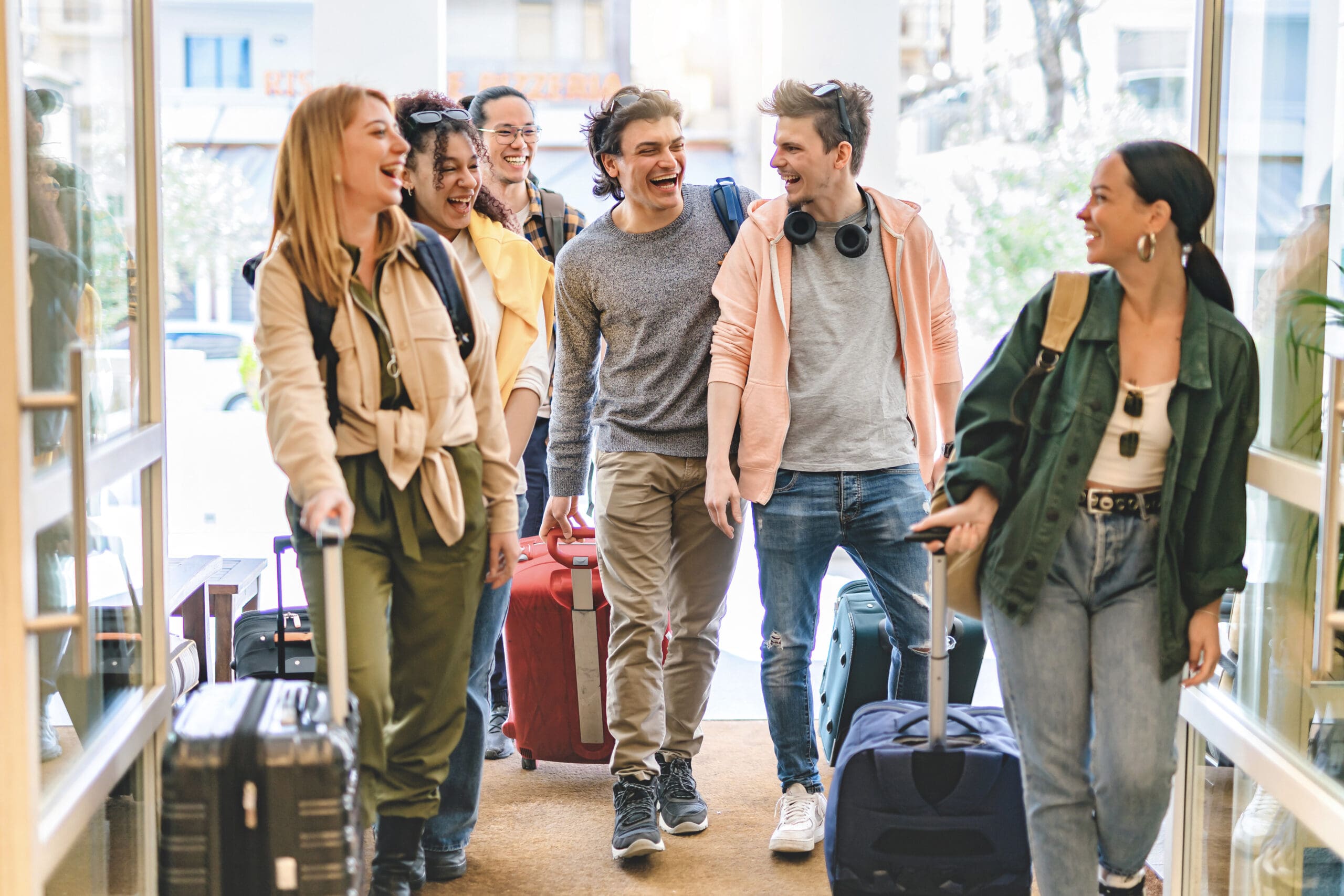 Group of university college tourist walking inside the hotel with suitcases -Young happy students enjoying summer holiday-Tourism Vacation and Lifestyle concept with people-Youth culture-Spring time