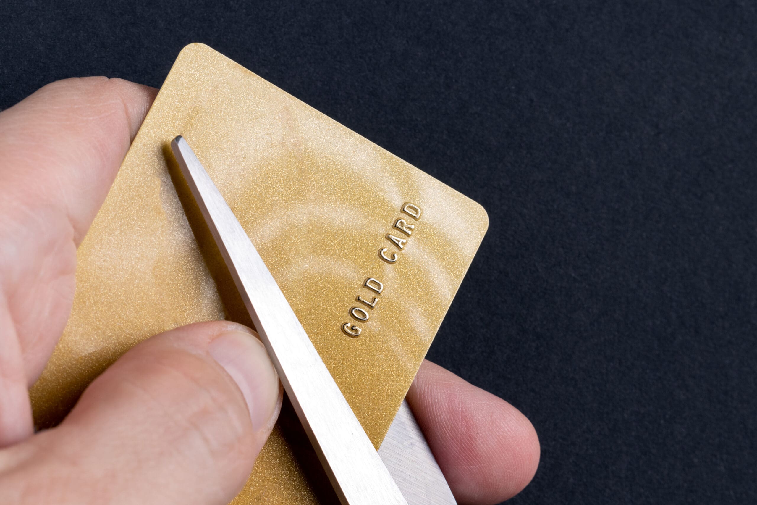 Man cuts a gold credit card with scissors. Sanctions. Financial fraud. Fraud with creditors cards. Stealing money from credit cards. Bankruptcy.