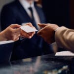 Close up of hotel receptionist giving room cardkey to African American hotel guest.