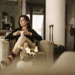 Businesswoman sitting at the airport lounge, waiting for the flight. Thoughtful woman sitting on sofa with coffee at airport waiting area.