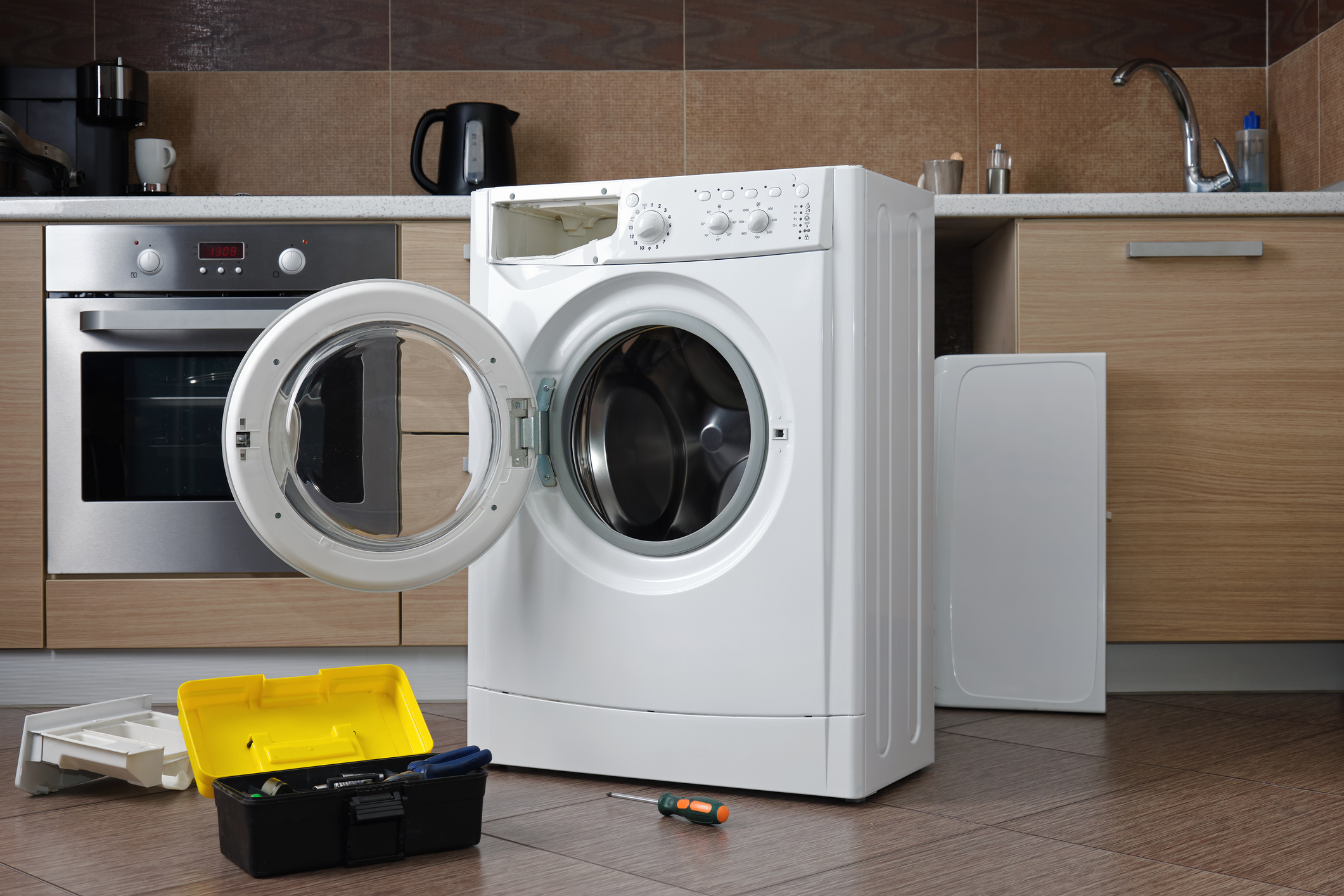 A disassembled household washing machine against the background of a home kitchen. Preparation for repair or maintenance.