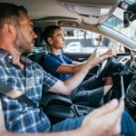 Driving instructor sitting his student and explain to him car driving basics, how to properly prepare himself for a drive. View from inside.