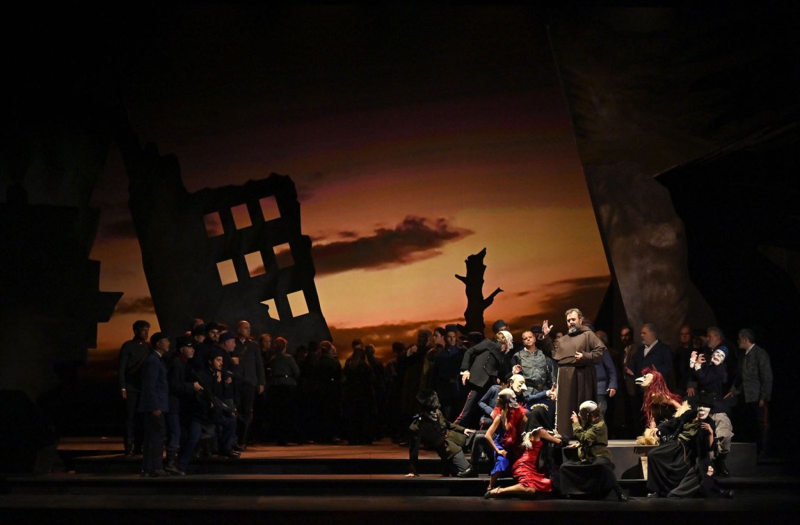 A friar addresses a crowd against a gloomy dusk backdrop