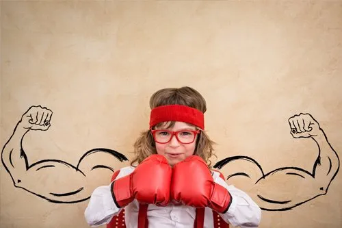 young girl wearing boxing gloves in front of drawing of muscular arms