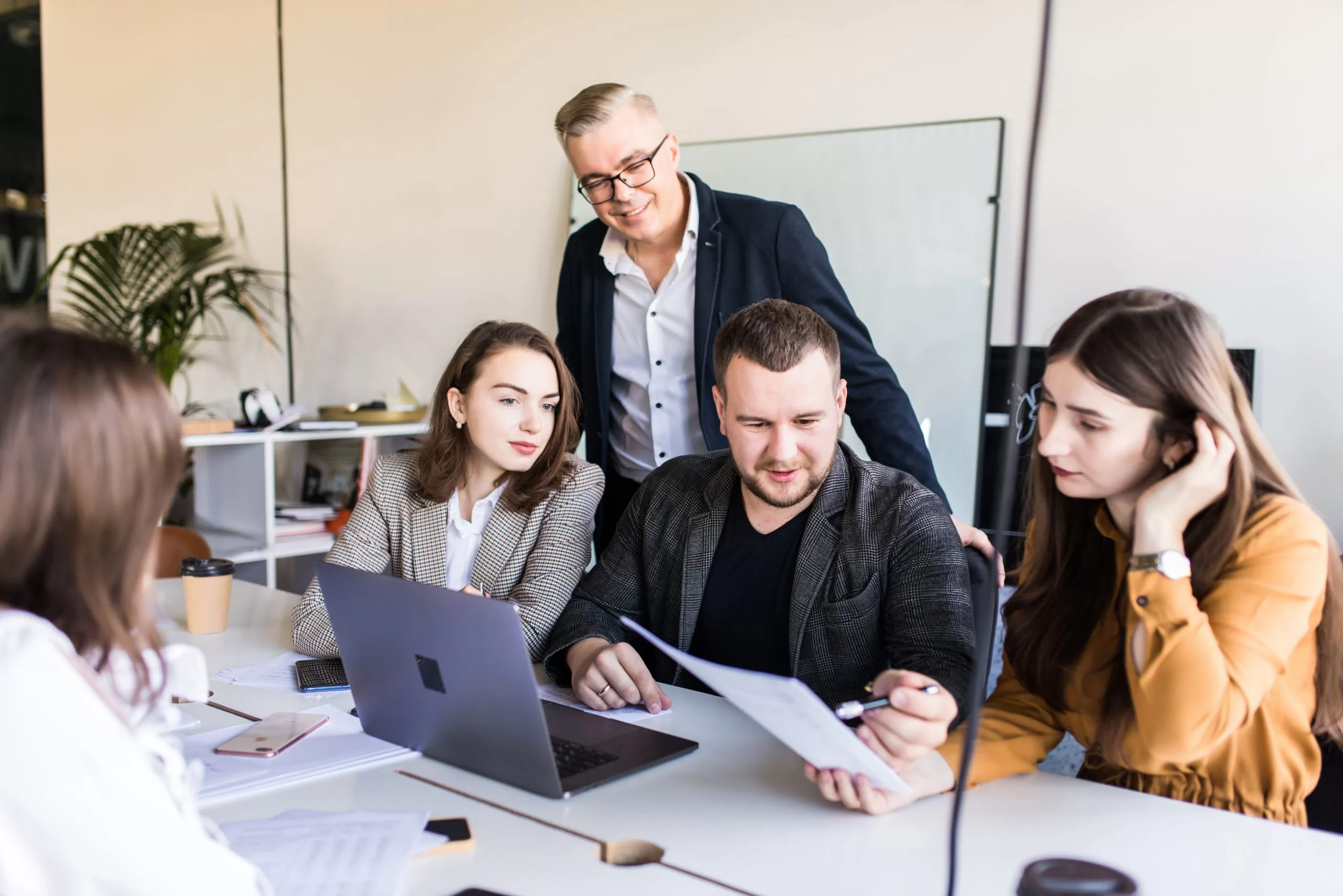 5 Employees are sitting around a desk and having a meeting.