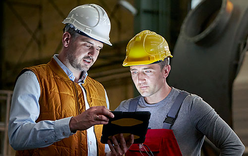 two people with helmet and uniforms in the factory