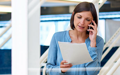 woman on the phone looking at the paper