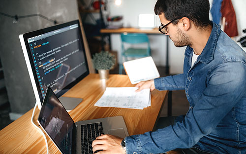 person working on two computers