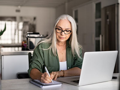 person writing down and a laptop in front of them