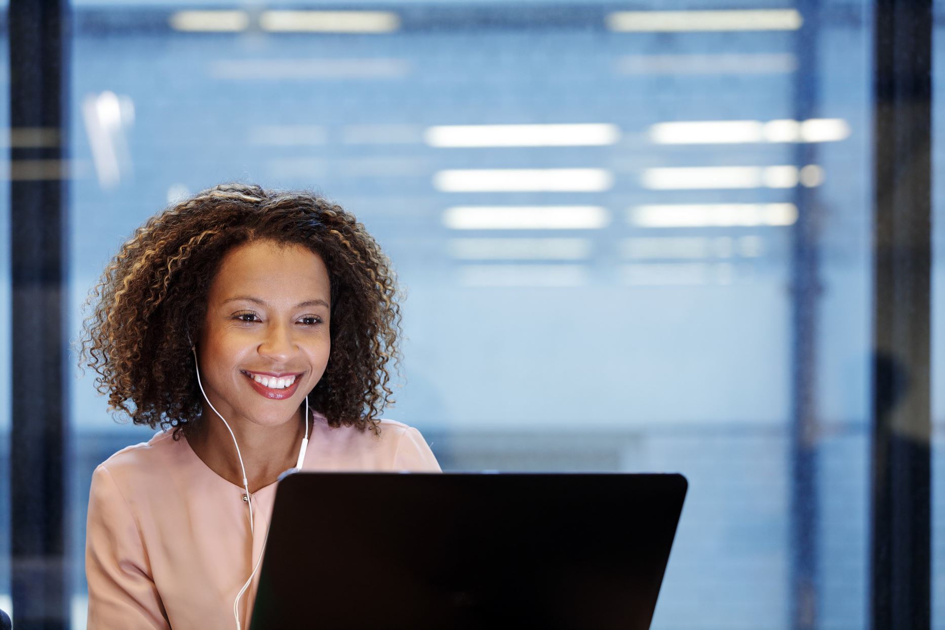 person with earphones looking at the laptop