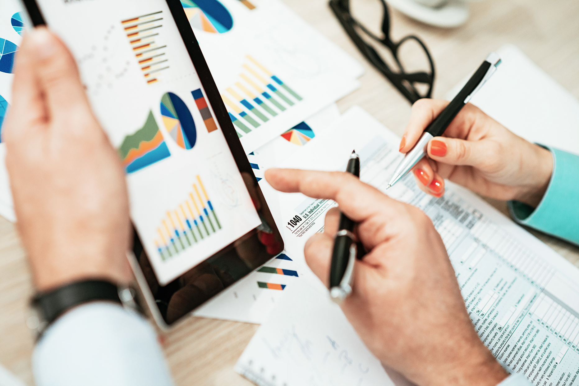 two people looking at papers and tablet with graphs on it