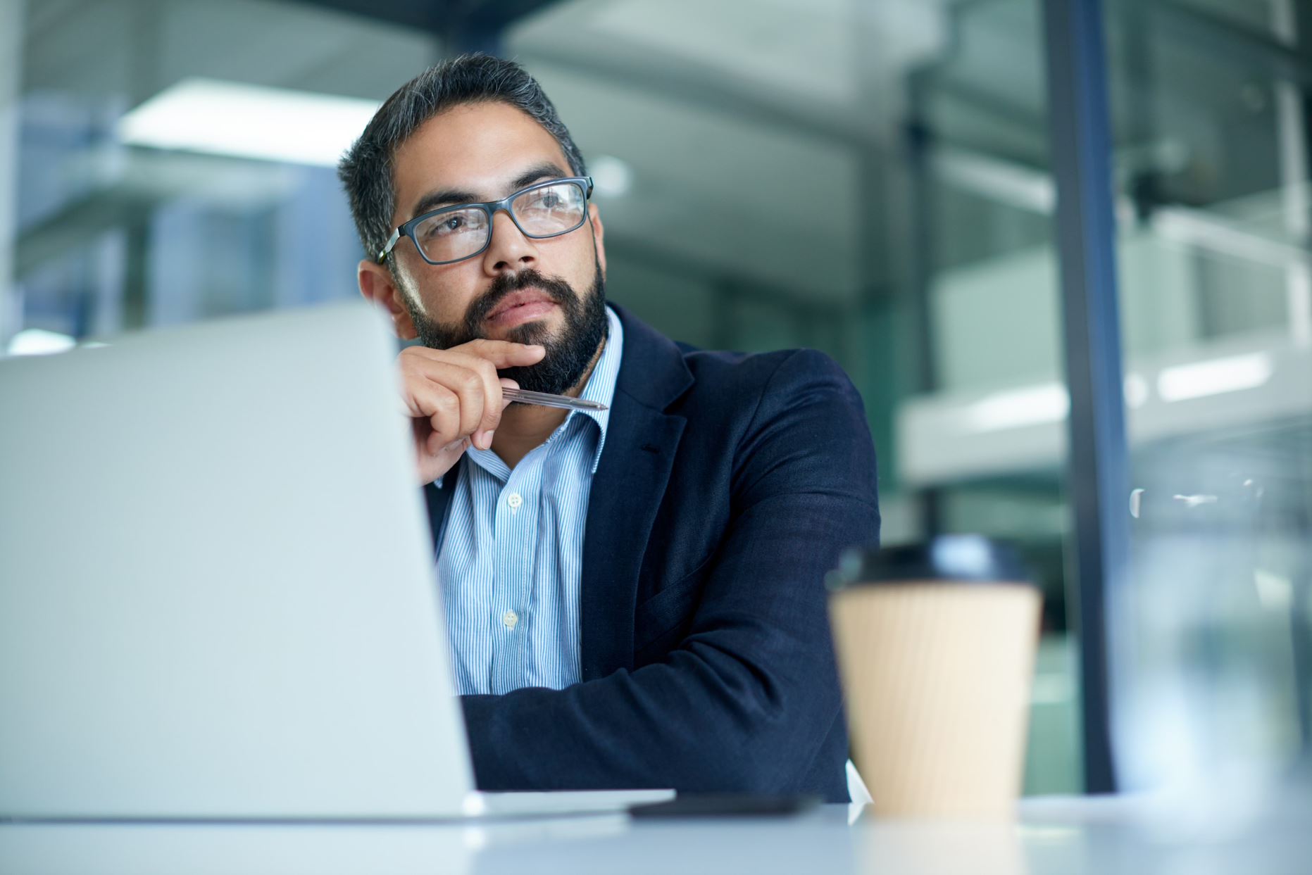 person staring outside with a laptop on coffee in front of him