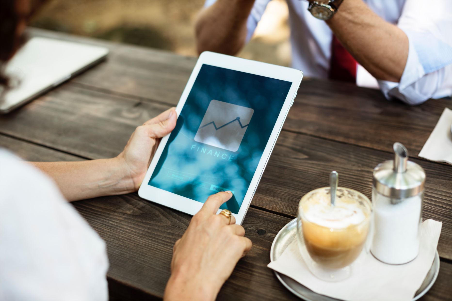 two people in a cafe holding a tablet with a graph on it