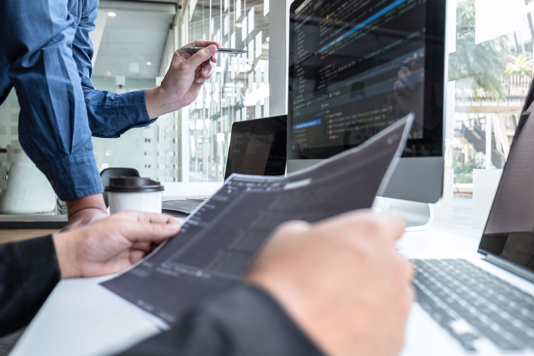 person with papers and computer looking at codes