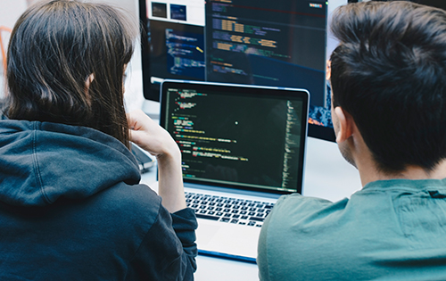 Man and woman wearing a black hoodie working on a laptop