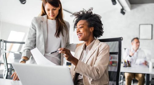 two women discussing a paper in an office setting