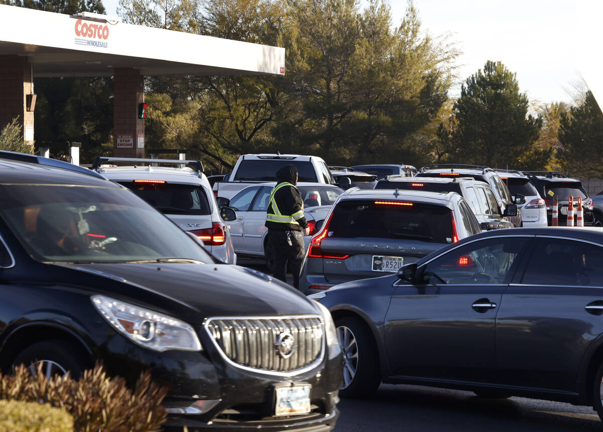 An employee directs traffic as people line up at a Costco gas station in Summerlin, on Friday. ...