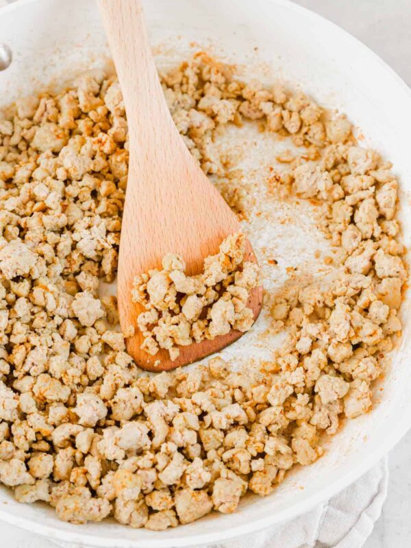 Fully cooked seasoned ground turkey meat in a skillet with a spatula.