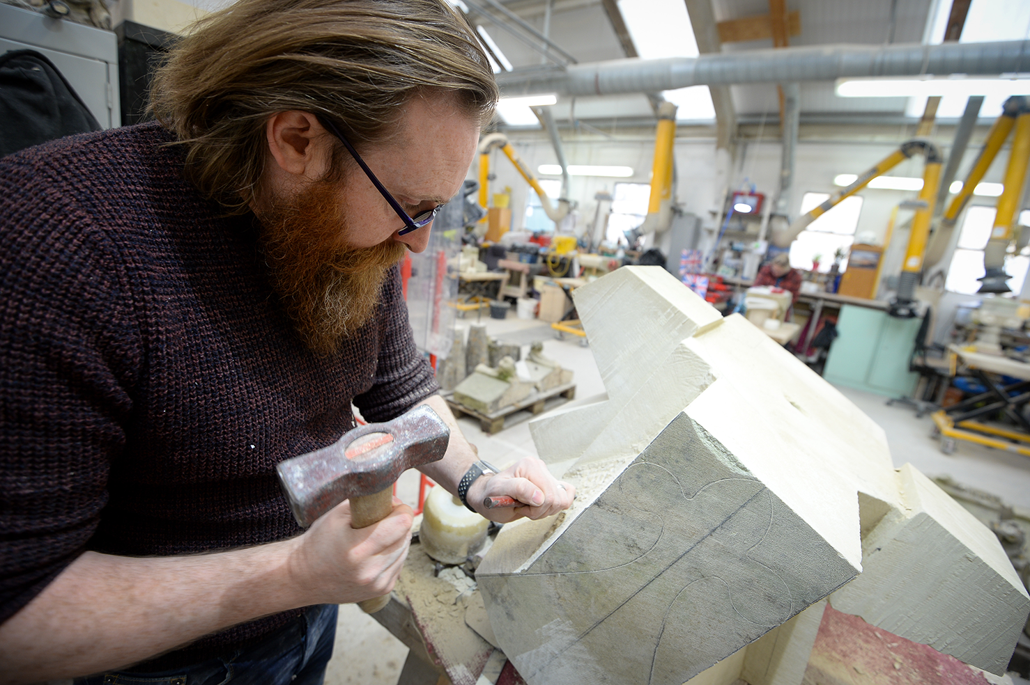 Man holding a tool working on carving a stone