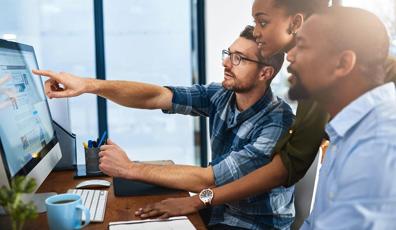 Three business people working around the computer in office