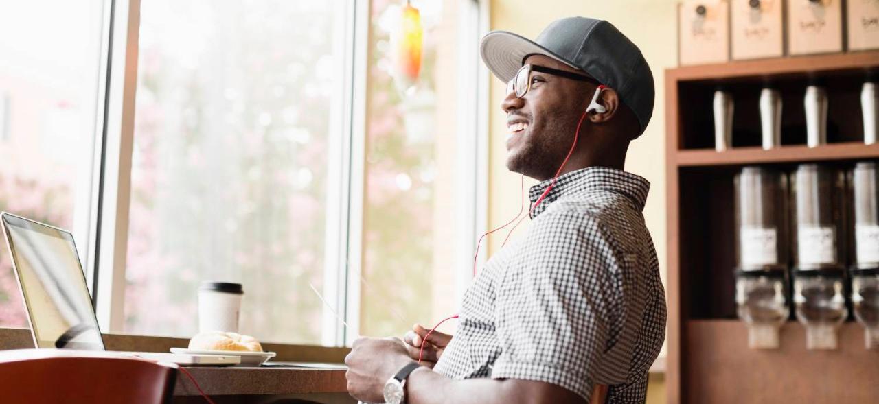 Man with hat and glasses on a phone call in coffee shop