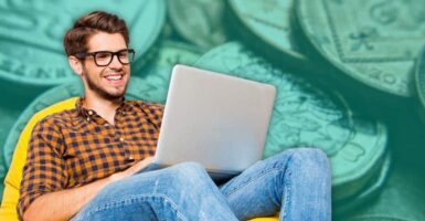 man using laptop with coins in background