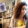 young woman sat using laptop next to money