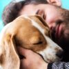 man cuddling dog looking happy