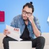 Man on sofa looking at paper with card and invoice