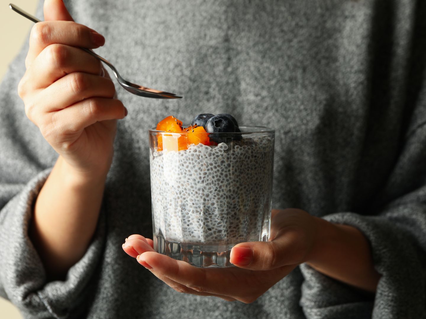 Woman holding chia seed pudding with blueberries and melon.