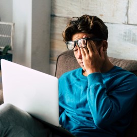 Stressed student at home studying with personal laptop computer