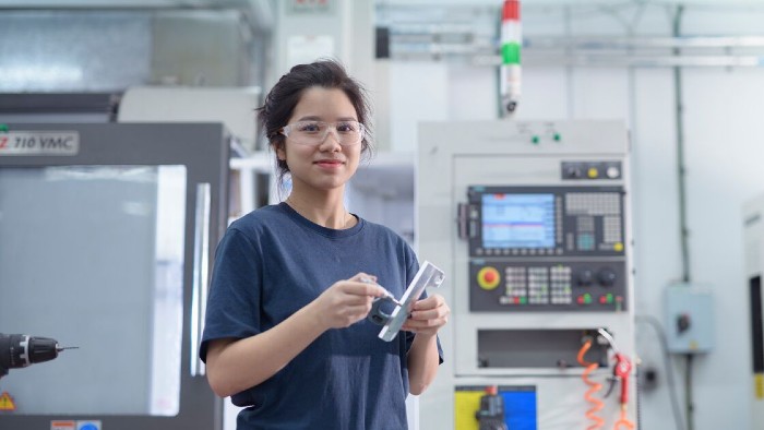 A student stood in a laboratory with a specialist tool in hand