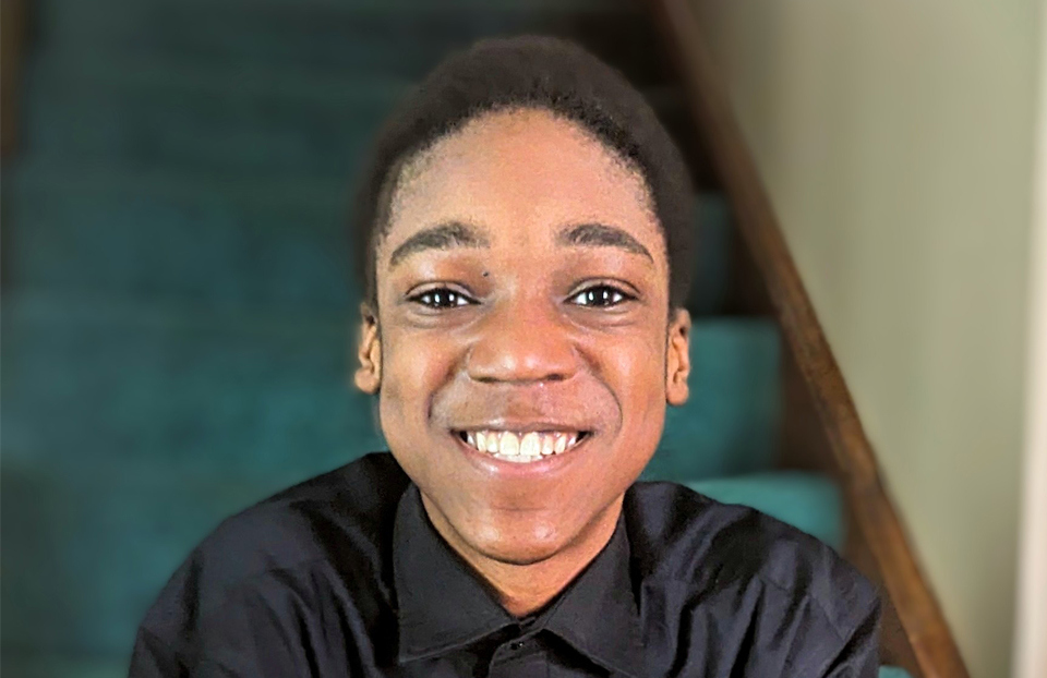 A young boy is smiling at the camera while sitting at green steps.