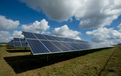 Solar panels under a blue sky with fluffy white clouds