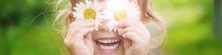 Girl holding flowers to her eyes.