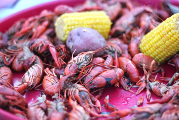 a close-up photo of a tray of boiled crawfish, red potatoes and corn on the cob