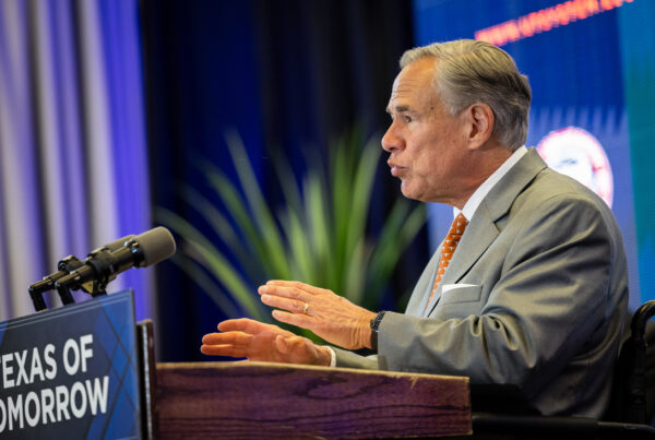 Texas governor Greg Abbot speaks at a podium with a sign on it that says "Texas of Tomorrow"