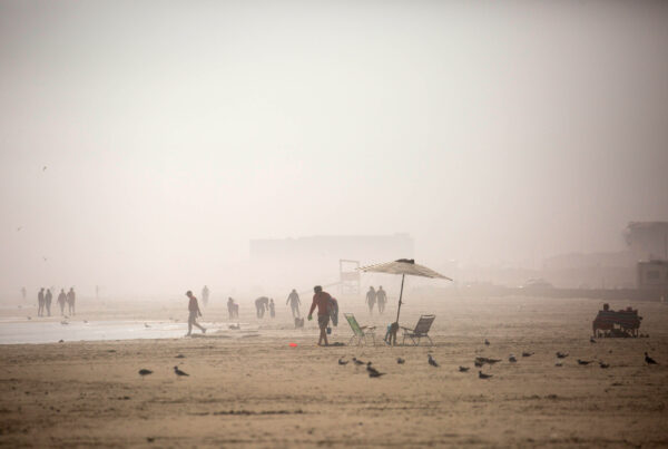 People are seen in the distance on a cloudy beach