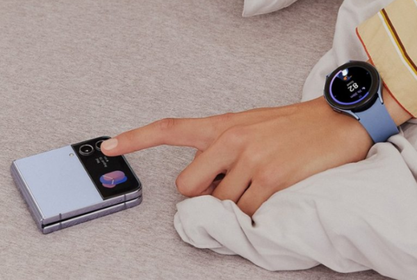 A hand wearing a Samsung smartwatch reaches to tap on a phone