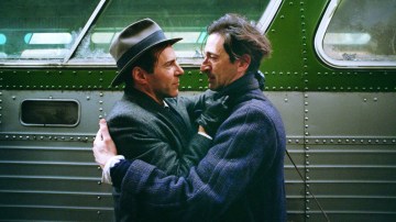 two men hugging in front of a green bus