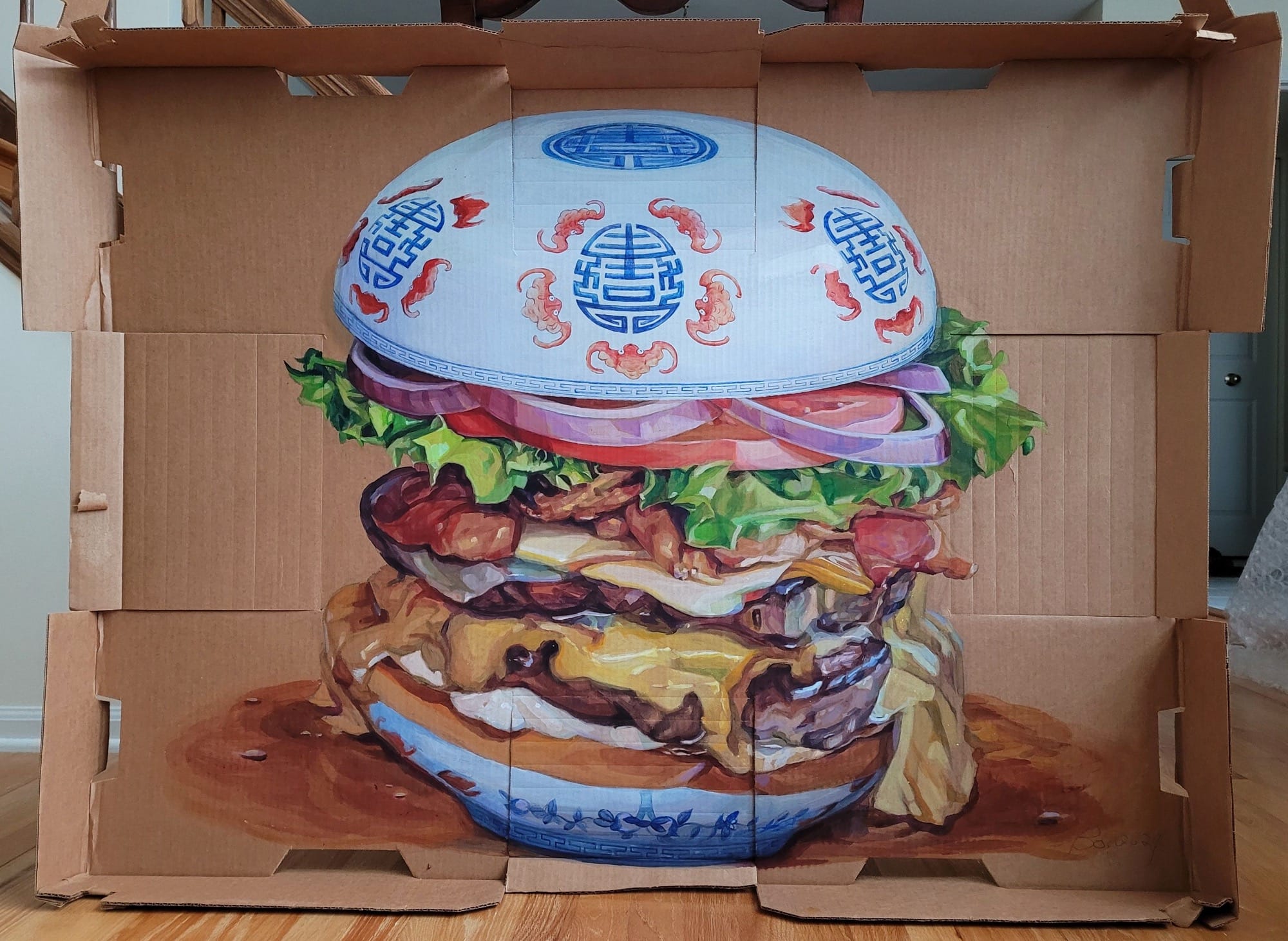 a painting of a juicy drippy burger with a blue and white porcelain style motif on the bun all on a cardboard box