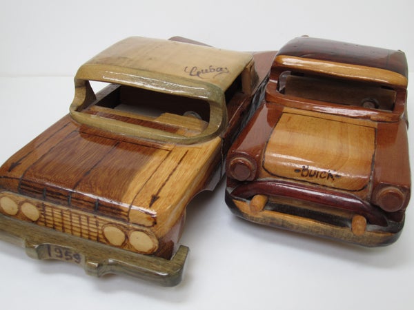 Two vintage wooden car models on a white background.