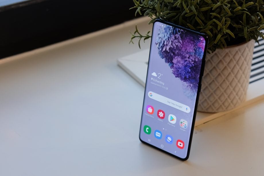 A Samsung Galaxy S20 Plus standing against a plant pot displaying homescreen