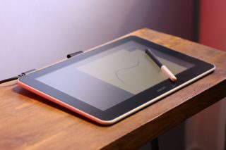 A Wacom tablet with its Pen kept on a wooden table