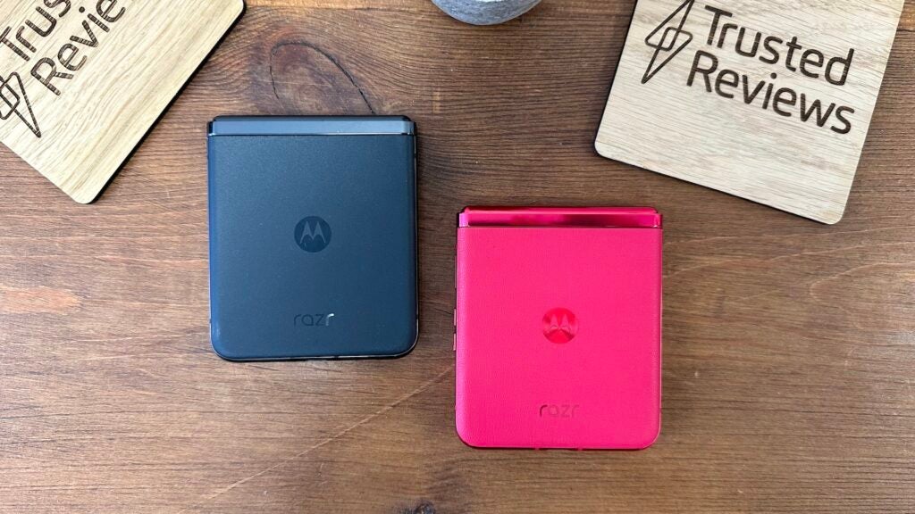 Rear of the black and viva magenta Motorola Razr 40 UltraMotorola Razr phones in black and pink on wooden surface.