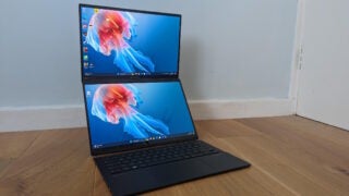 Asus Zenbook Duo laptop with dual screens on a wooden floor.