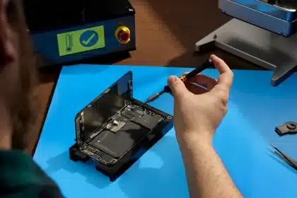 Person repairing an iPhone using tools on a workbench.