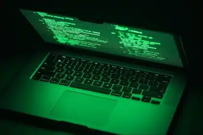 Green-lit laptop screen displaying code.