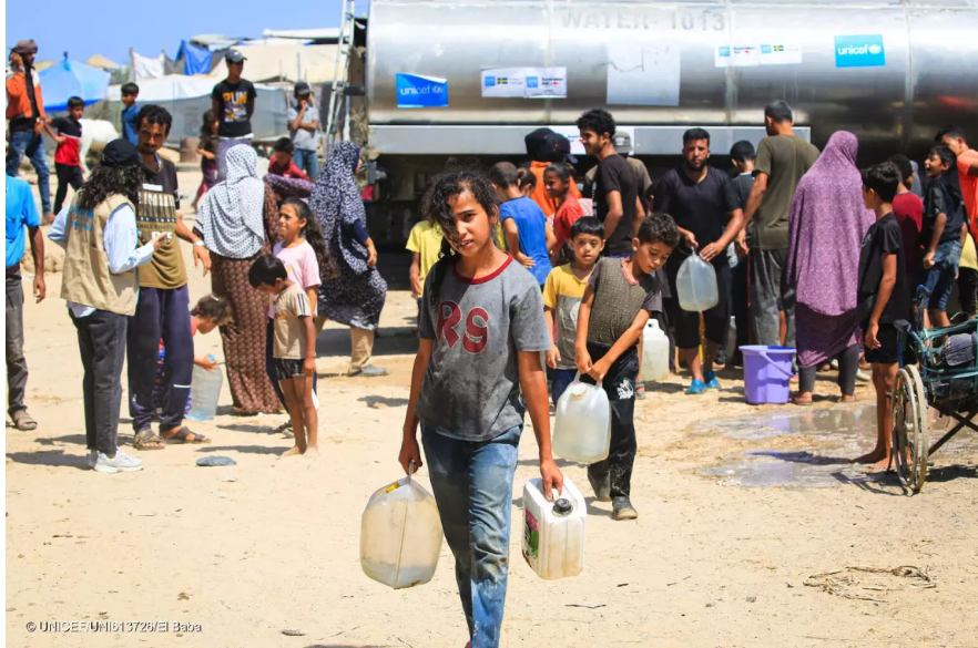 Jana holds two containers after filling them at a UNICEF-supported water tank in the Gaza Strip.